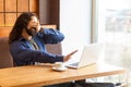 Scared bearded young man freelancer in casual style and long curly hair sitting and talking with his friend in laptop, covering