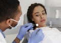 Scared black woman looking at dental tools in doctor hands Royalty Free Stock Photo