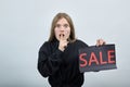 Scared woman, keeping adverising sale, keeping hand on chin, doing shh gesture Royalty Free Stock Photo