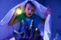 Scared boy with a flashlight hides under the blanket from the hand of a scary monster. Nightmare for children Royalty Free Stock Photo