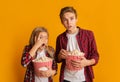 Scared brother and sister holding popcorn buckets and looking at camera Royalty Free Stock Photo