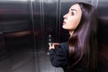 scared businesswoman, suffering from claustrophobia, looking up while pushing button in elevator.