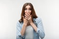 Scared caucasian girl with long chestnut hair covering mouth with hands on white background. Keep silence concept Royalty Free Stock Photo