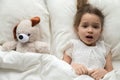 Scared child lying in bed with toy afraid of nightmare