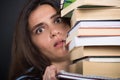Scared female student carrying a pile of books Royalty Free Stock Photo