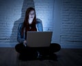 Scared female teenager with computer laptop suffering cyberbullying and harassment being online abused