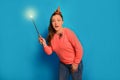 Scared Halloween witch woman conjuring by luminous magic wand or glowing magic stick with spider on blue background.