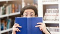 Scared korean guy hiding behind book in library Royalty Free Stock Photo