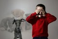 Scared little boy suffering from cynophobia on background. Irrational fear of dogs