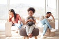 Scared little kid with afro sitting and holding teddy bear while parents fight. African American couple ignoring each