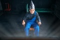 Scared man in aluminum foil hat sits in chair Royalty Free Stock Photo