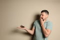 Scared man holding tarantula on background, space for text. Arachnophobia fear of spiders Royalty Free Stock Photo