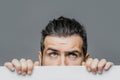 Scared man with paper. Young bearded man pointing in blue background at copy space.