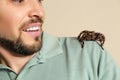 Scared man with tarantula on beige, closeup. Arachnophobia fear of spiders Royalty Free Stock Photo
