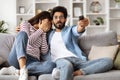 Scared millennial couple sitting on couch at home, watching horror Royalty Free Stock Photo