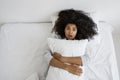 Scared mixed race woman lying on bed, hug pillow Royalty Free Stock Photo