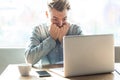 Scared or nervous! Portrait of emotional nervous young businessman in blue shirt are sitting in cafe working online and nail Royalty Free Stock Photo