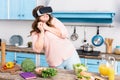 scared overweight woman in virtual reality headset standing at table with fresh vegetables in kitchen Royalty Free Stock Photo