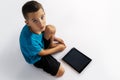 Scared seven years old boy sits down on the floor close to tablet computer with broken screen glass. Royalty Free Stock Photo