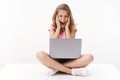 Scared terrified young cute caucasian blond girl scream from fear, sit crossed legs hold laptop, close eyes and shouting Royalty Free Stock Photo