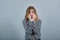 Scared woman in black and white striped shirt looking at camera, biting nails Royalty Free Stock Photo