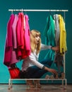 Scared woman hiding among clothes in mall wardrobe Royalty Free Stock Photo