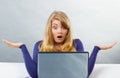 Scared woman shrugging shoulders and looking at laptop, computer problem Royalty Free Stock Photo