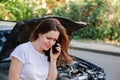 Scared woman in stress after auto crash calling to auto insurance for help. Driver woman crying in front of wrecked car Royalty Free Stock Photo