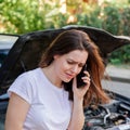 Scared woman in stress portrait near auto crash calling to auto insurance for help. Driver woman crying in front of wrecked car in