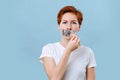 Scared woman untaping her mouth over blue Royalty Free Stock Photo