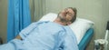 scared and worried man hospitalized - attractive injured man lying on hospital bed receiving treatment sick and unwell