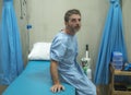 Scared and worried man hospitalized - attractive injured man sitting on hospital bed receiving treatment feeling sick and unwell