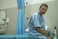 Scared and worried man hospitalized - attractive injured man sitting on hospital bed receiving treatment feeling sick and unwell Royalty Free Stock Photo