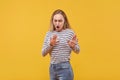 Scared young blonde woman with her mouth open. Yellow background. Royalty Free Stock Photo