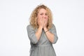 Scared young curly woman covering mouth with hands being scared. Royalty Free Stock Photo