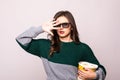 Scared young girl in 3d imax glasses covering face with palm, watching movie film, holding bucket of popcorn isolated on white