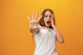 Scared young teen girl showing stop gesture against yellow background Royalty Free Stock Photo