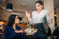 Scared young waitress look at salad bowl brunette hold in hands. She show her this food. Young woman in blouse is Royalty Free Stock Photo