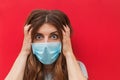 Scared young woman in medical mask standing over red background. Royalty Free Stock Photo