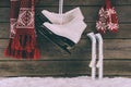 Scarf with gloves and white skates hanging on wooden wall