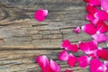 Scarlet rose petals scattered on the old wooden table Royalty Free Stock Photo