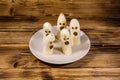 Scary banana ghosts in ceramic plate on a wooden table. Halloween concept