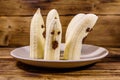 Scary banana ghosts in ceramic plate on a wooden table. Halloween concept