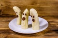 Scary banana ghosts in ceramic plate on a wooden table. Halloween concept