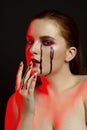 Scary beauty Halloween makeup portrait of a beautiful red hair girl with red eye shadows and fake blood from yellow eyes Royalty Free Stock Photo