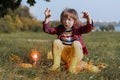 Scary boy in glasses play with shine light pumpkin in autumn park on Halloween. Kids trick or treat. Fun in fall. Dressed up child