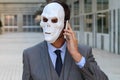 Scary businessman wearing a mask calling by phone Royalty Free Stock Photo