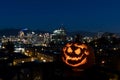 Scary carved pumpkin with a city view background
