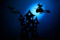 Scary castle silhouette,black paper bats and witch on broom flying on dark blue background.