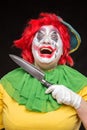 Scary clown joker with a smile and red hair with a big knife on